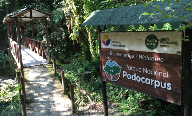 Photo of the welcome sign to Podocarpus National Park by a wooden bridge.