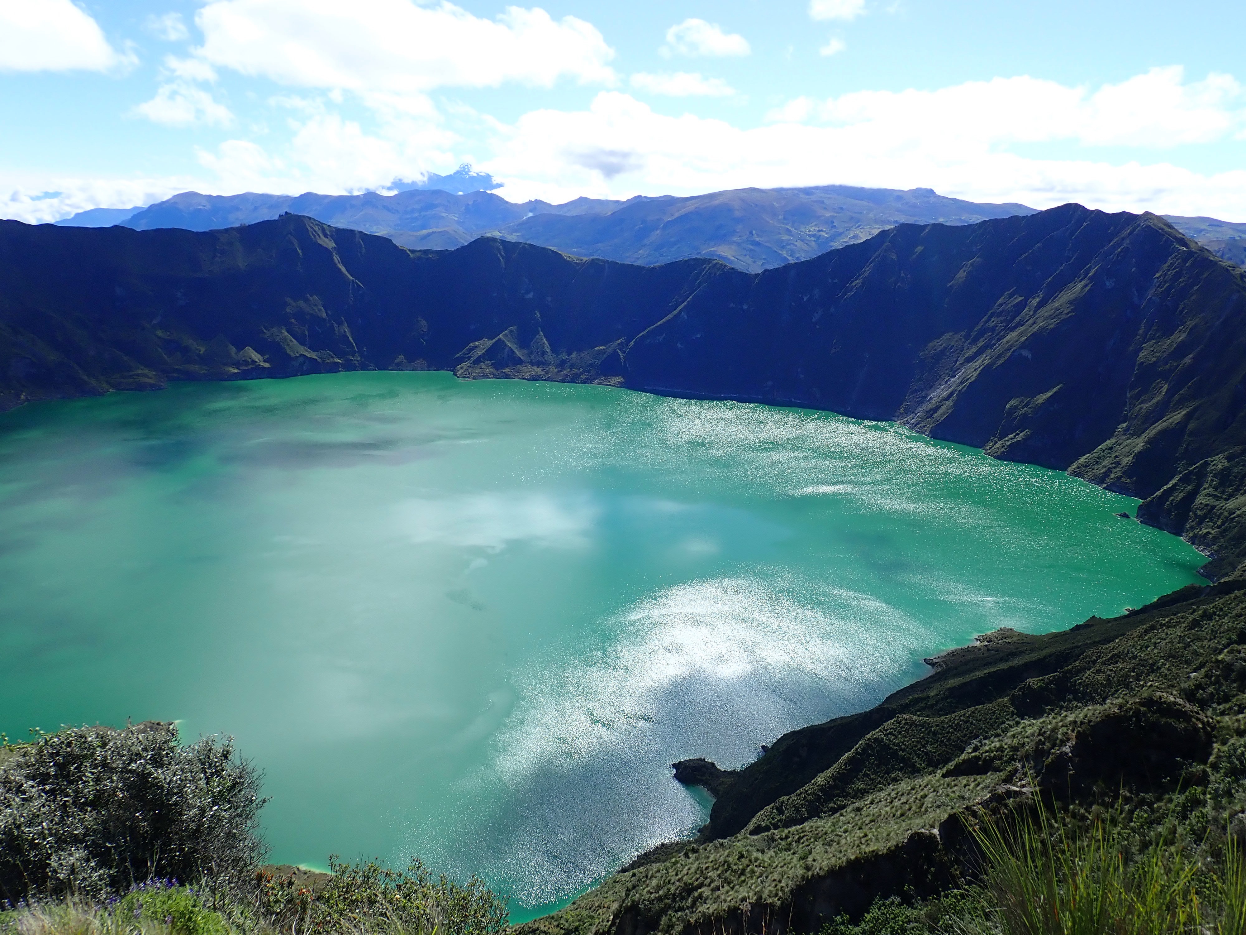 photo of a bright green lake in the crater of craggy ridges